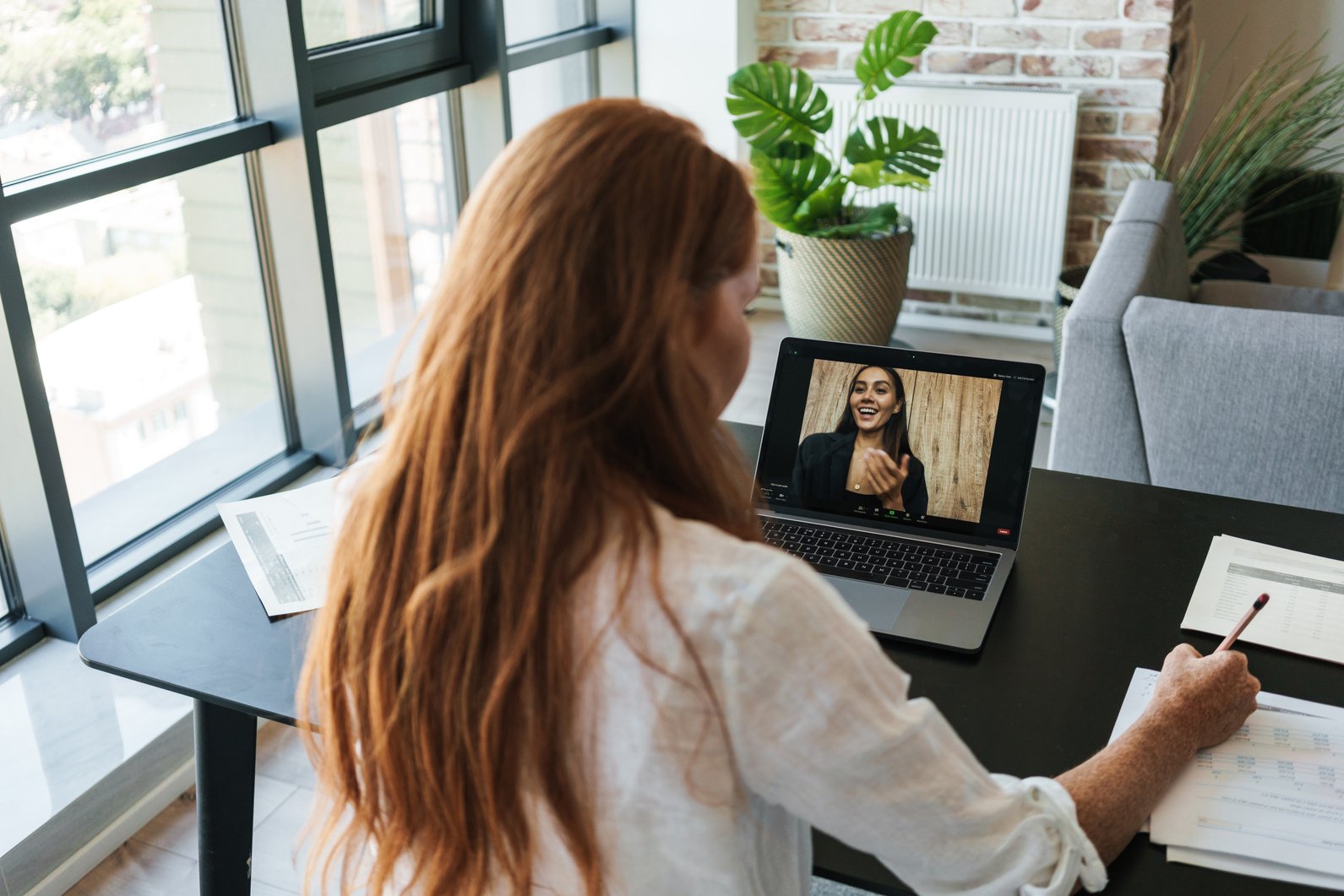 Image of Businesswoman Making Call on Laptop While Sitting at Table